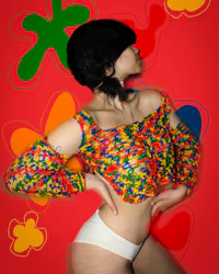 a woman in a colorful top posing on a colorful background