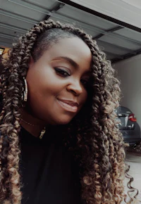 a woman with curly hair standing in front of a garage