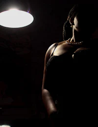 a woman in a black dress standing in front of a light