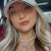 a woman wearing a hat and necklace in a car