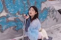 a woman crouching in front of a wall covered in graffiti