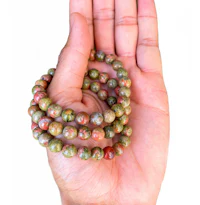 a person holding a hand full of green and red beads