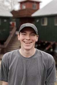 a young man smiling in front of a building