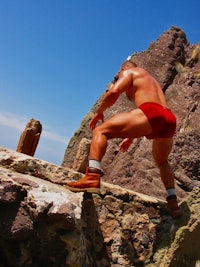 a man in a red underwear standing on a rock