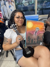 a woman sitting in a chair holding a ukule