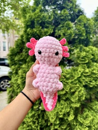 a person holding a pink crocheted stuffed animal