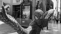 a black and white photo of a spider - man on the street