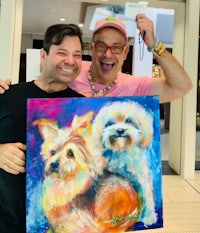 two men holding up a painting of dogs