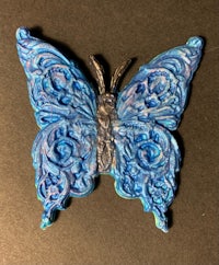 a blue butterfly brooch on a black surface