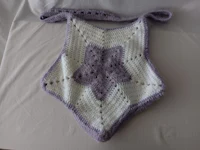 a purple and white crocheted bag on a bed