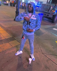 a man in a blue hoodie standing on a street at night