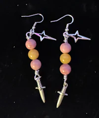 a pair of earrings with a sword and pink beads