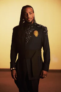 a man in a suit with dreadlocks posing for a photo