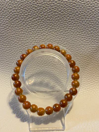 a bracelet with brown jade beads on a white surface