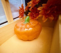 an orange pumpkin sits on a window sill