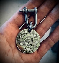 a person holding a metal keychain with a skull on it