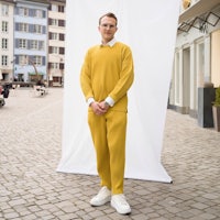 a man in a yellow sweater standing in front of a building