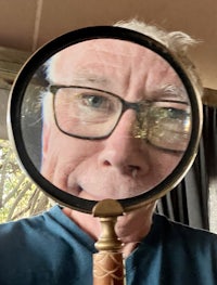 a man with glasses looking through a magnifying glass