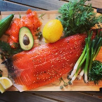 salmon on a cutting board with lemons and herbs