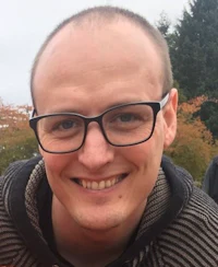 a man in glasses smiles for the camera