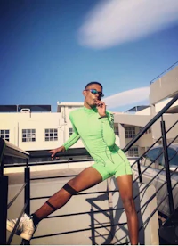 a young man in a green suit is posing on a staircase