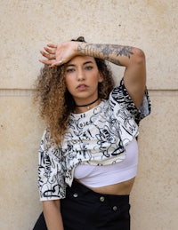 a woman with tattoos leaning against a wall