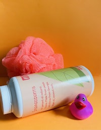 a pink rubber duck sits next to a bottle of green tea body wash