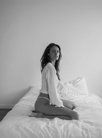 a woman in white lingerie sitting on a bed