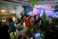 a group of people are standing in a room with plants
