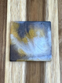 a small square of yellow and white paint on a wooden surface