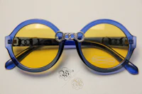 a pair of blue and yellow sunglasses on a white surface