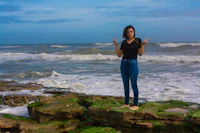 a woman standing on a rock in the ocean