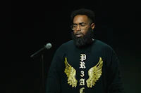 a black man with a beard and a microphone