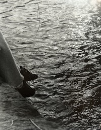 a person sitting on a rock next to a body of water