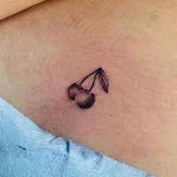a small cherry tattoo on a woman's stomach