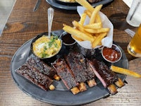 ribs and fries on a plate on a wooden table