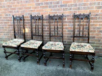 four victorian dining chairs with upholstered seats against a brick wall
