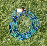 a blue and green beaded bracelet laying on the grass
