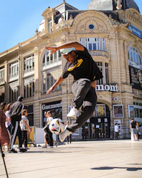 a man doing a trick on a soccer ball in front of a building