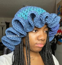 a woman wearing a crocheted ruffled hat