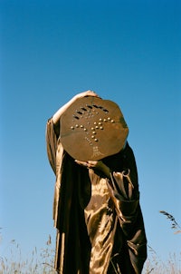 a person in a robe standing in a field holding a frisbee
