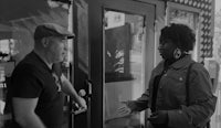a black and white photo of a man talking to a woman