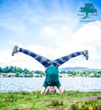 a woman doing a handstand in front of a lake