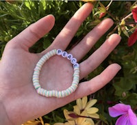 a person holding a bracelet with the word peace on it