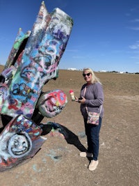 a woman standing next to a group of sculptures in a field