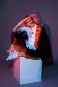 a man sitting on a cube with his hands on his head
