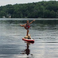 a woman on a stand up paddle board with a dog