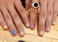 a woman's hands with colorful nails and a ring on them