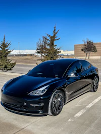 a black tesla model 3 parked in a parking lot