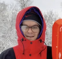 a man in a red jacket with an orange snow shovel